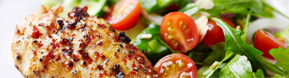 Imagem de um frango assado acompanhado de uma salada de agrião e tomate