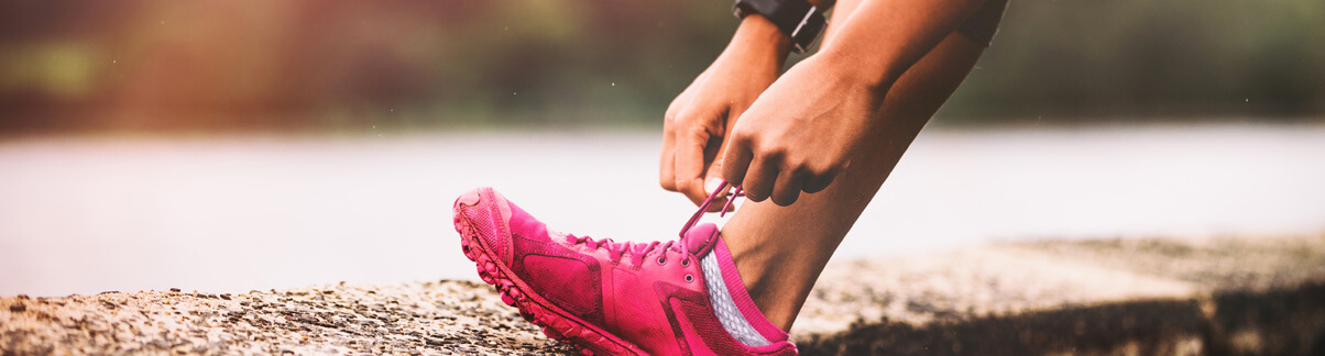 Pessoa amarrando o tênis se preparando para caminhar