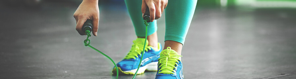 Imagem dos pés e mãos de uma pessoa se preparando para pular corda