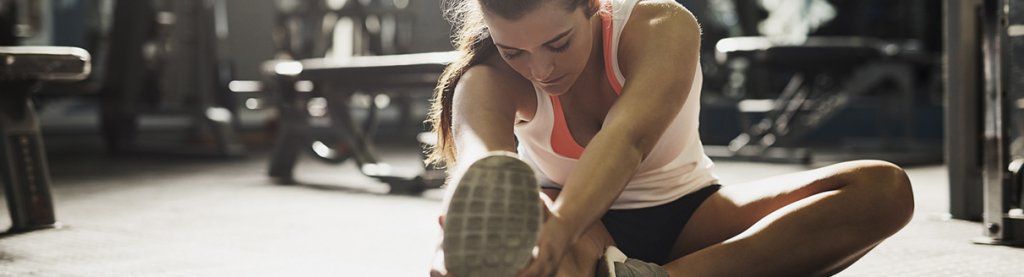 Mulher com roupa de corrida fazendo alongamento dos pés: atividade física