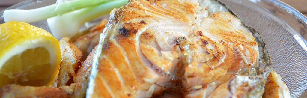 Imagem de um peixe grelhado com uma fatia de limão ao lado