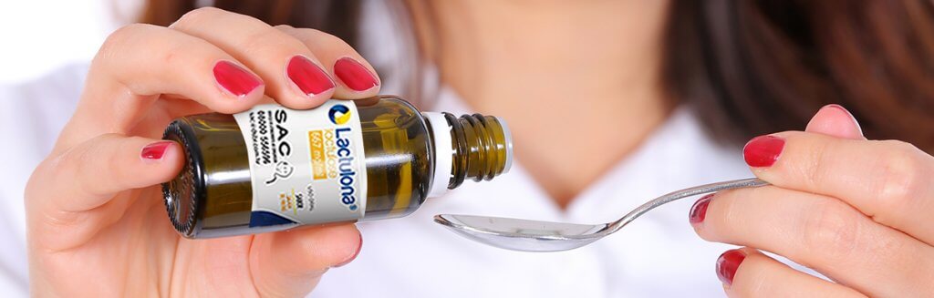 Pessoa colocando dose de Lactulona em uma colher de metal