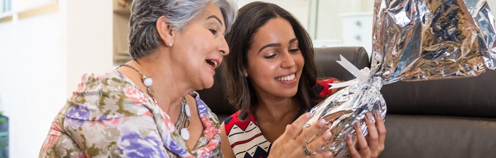 Mulher idosa presenteando pessoa mais jovem com um ovo de páscoa