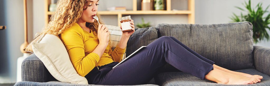 Mulher sentada em um sofá comendo chocolate 