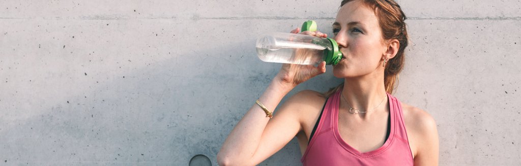 Mulher tomando água em uma garrafa