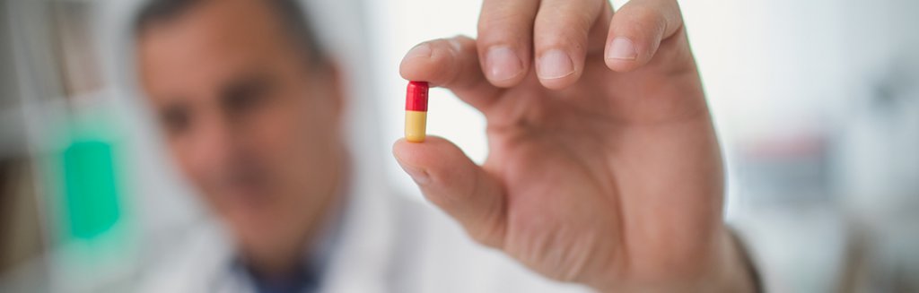 Médico desfocado segurando um comprimido