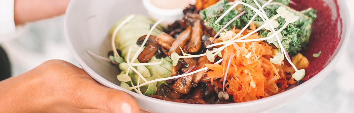 Tijela com alimentos saudáveis como cenoura, brócolis e cogumelos