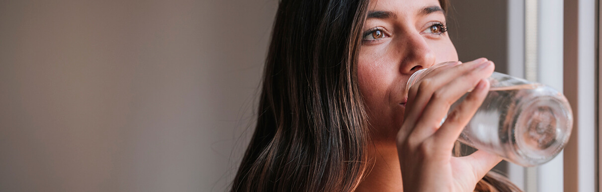 Mulher olhando para a frente e bebendo água