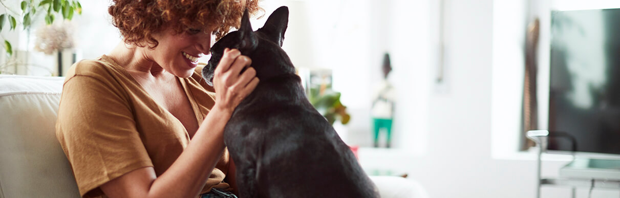 Mulher fazendo carinho em um cachorro e sorrindo