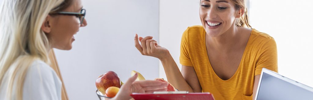 Nutricionista e paciente em consultorio com frutas e computador: orientação nutricional
