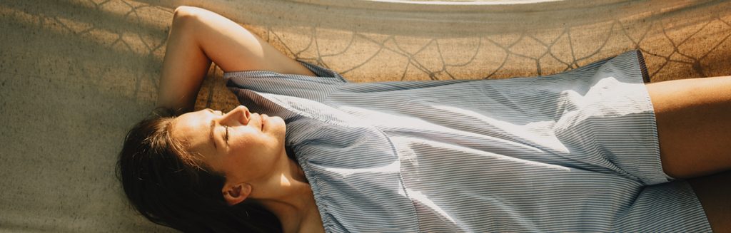 Mulher acordando com o sol no rosto na rede