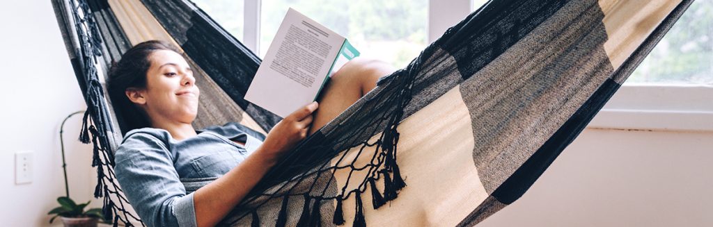 Mulher deitada na rede lendo um livro