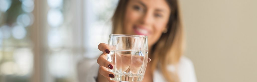 Mulher sorrindo segurando um copo de água