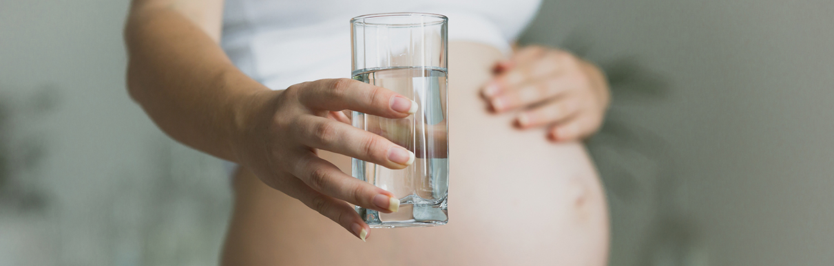 Mulher grávida com um copo de água na mão