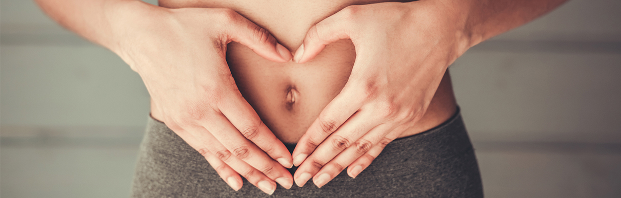 Pessoa com as mãos na barriga em formato de coração