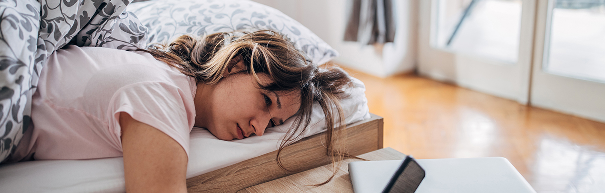 Mulher deitada com os cabelos bagunçados e uma feição de desagrado