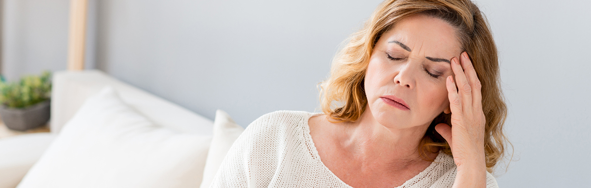 Mulher com a mão na cabeça e feição de desconforto