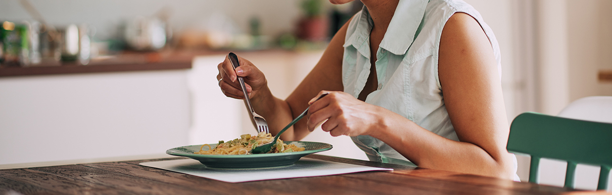 Pessoa sentada em uma mesa prestes a almoçar