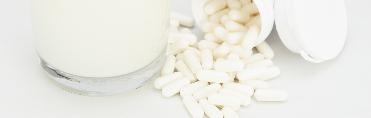 Diversos comprimidos ao lado de um copo de leite