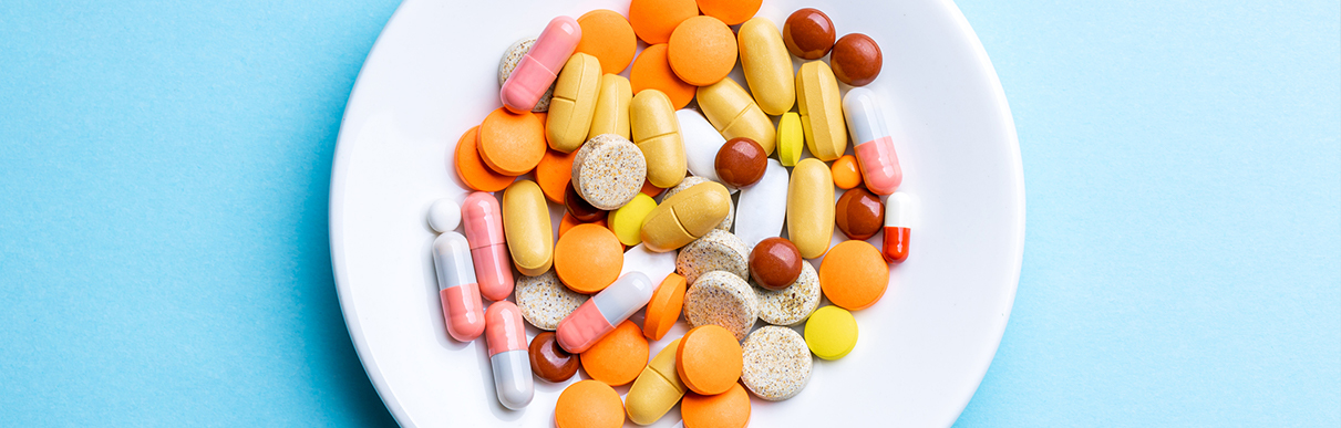 Diversos comprimidos diferentes em um prato em uma superfície azul