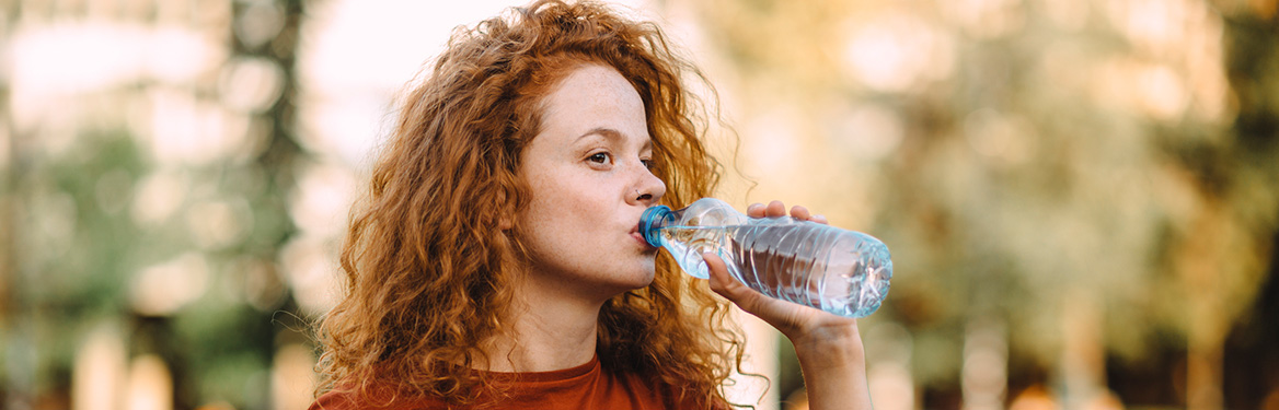 Mulher ruiva bebendo água em uma garrafa