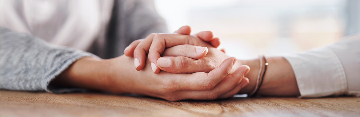 Duas pessoas segurando as mãos uma da outra demonstrando apoio