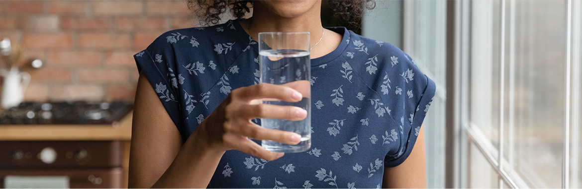 Mulher de blusa azul segurando um copo de água